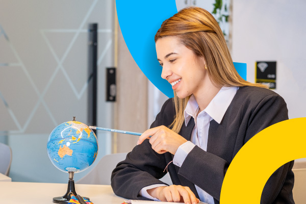 Estudiante sonríe mientras estudia con un globo terráqueo en la CET.