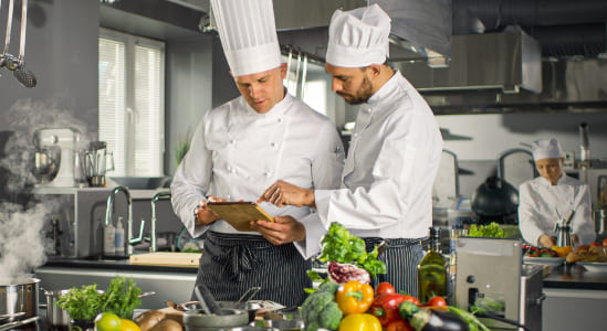 Dos chef egresados del técnico en cocina revisando una receta.